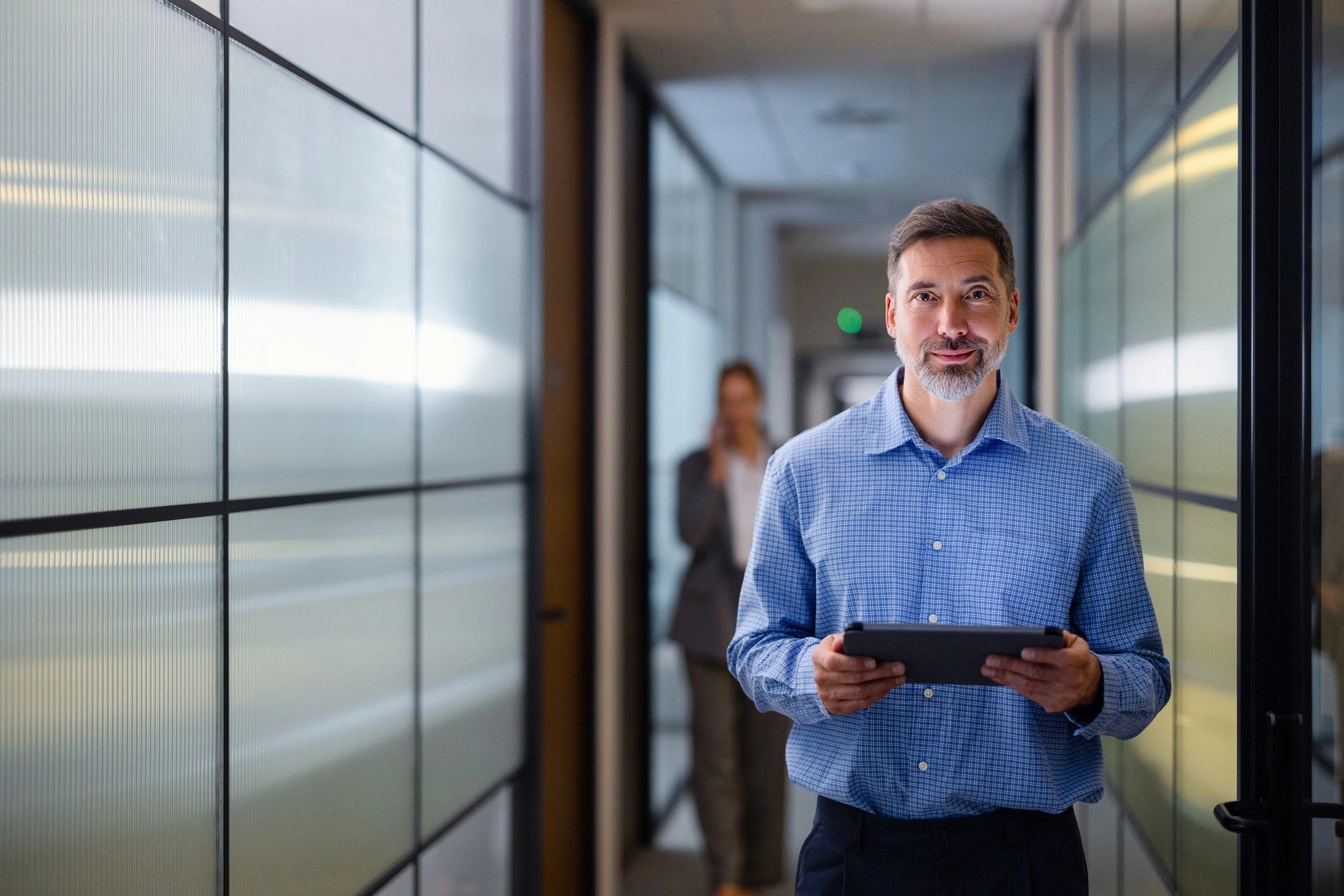 Businessman holding a tablet in a modern office hallway